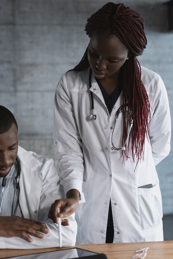 Black male and female doctors collaborating in a medical clinic with a tablet.